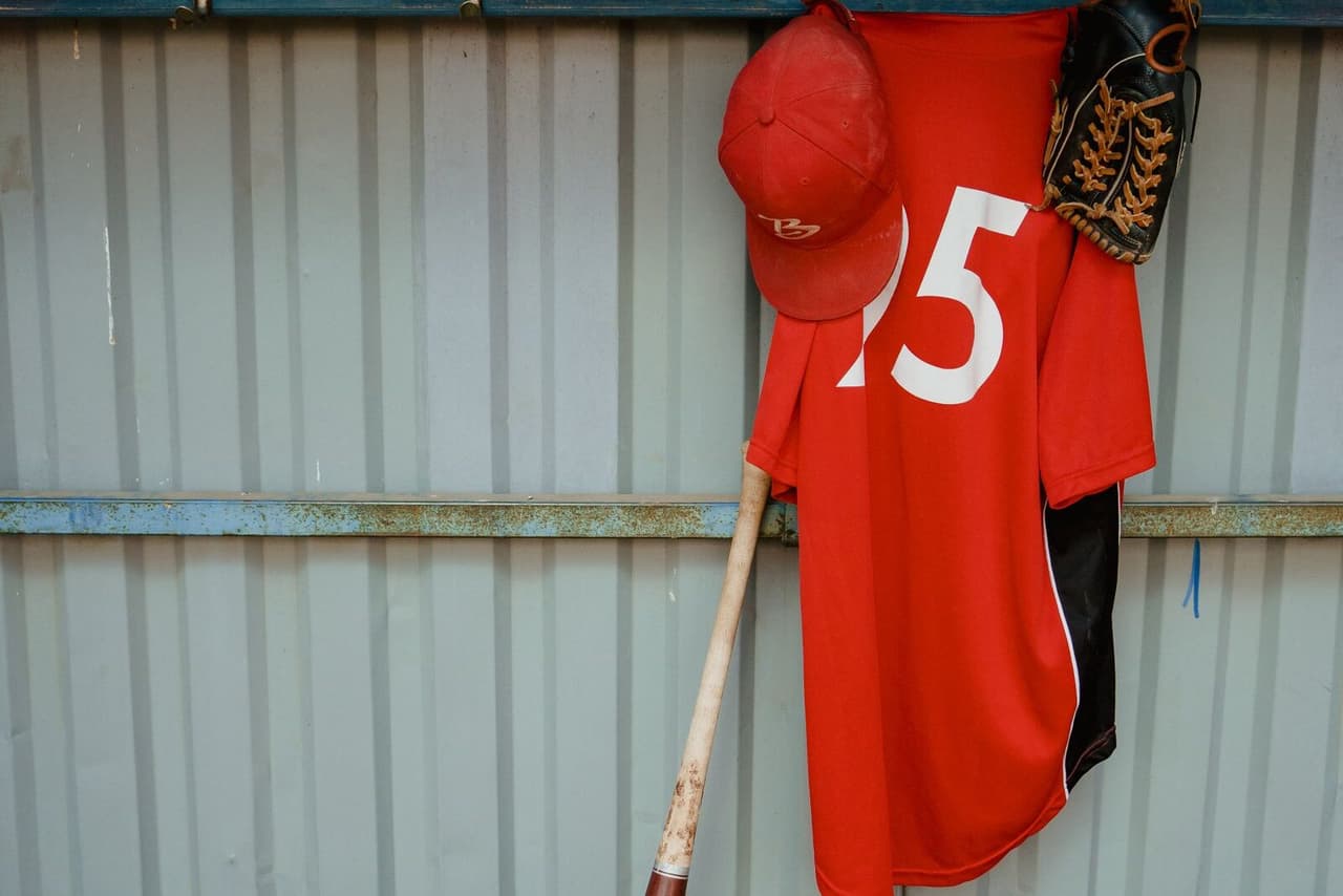 A team jersey, bats and baseballs in a dugout