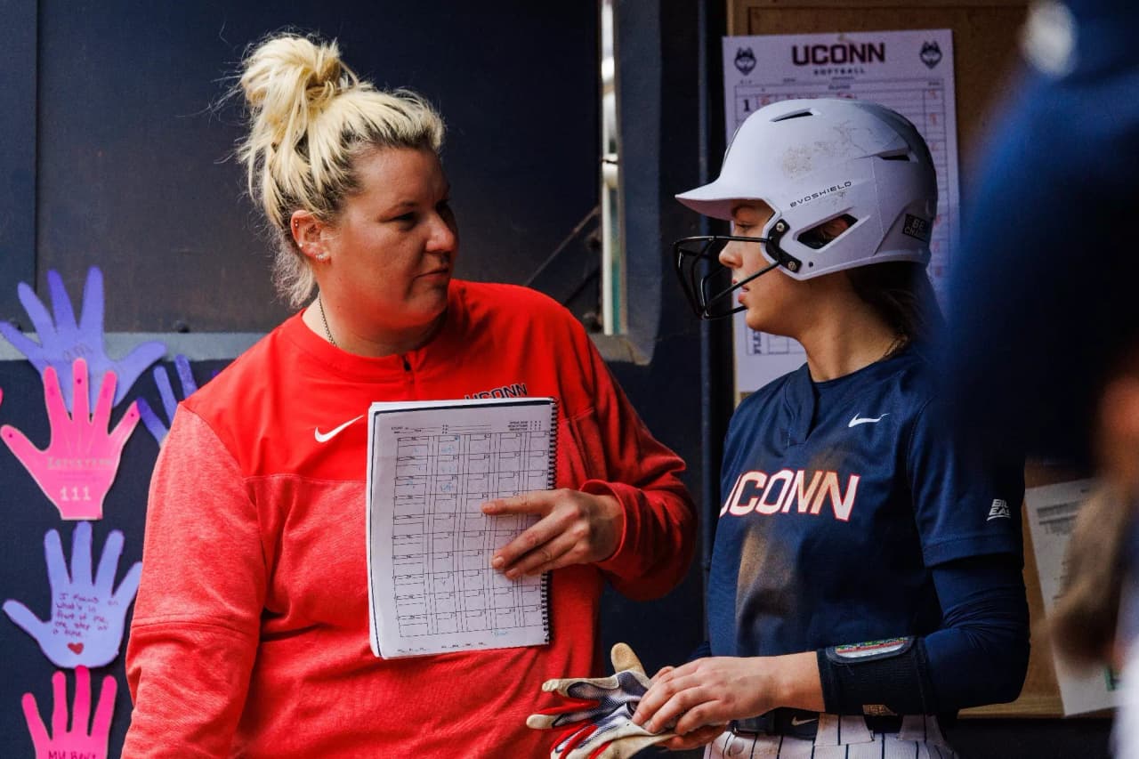 Softball coach discussing lineup strategy with team on field