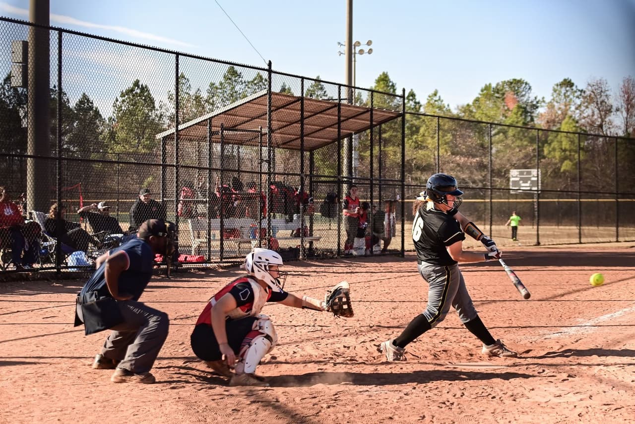 Fastpitch softball player at the plate holding a bat, ready to hit