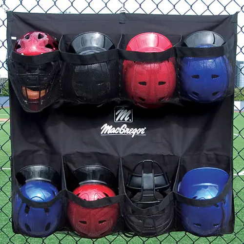 Baseball helmets, gloves, and batting gloves hanging on fence hooks along a chain-link dugout fence, keeping the bench and floor clear