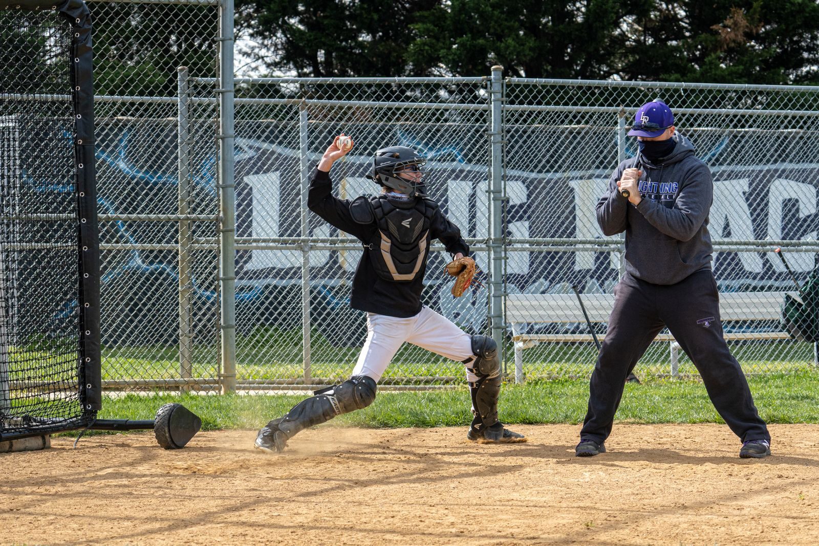 Coach running a soft toss hitting station at youth baseball practice