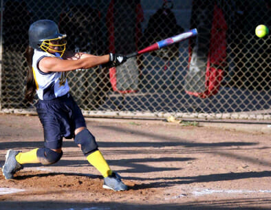 Youth softball players warming up with soft toss and partner drills before a practice session