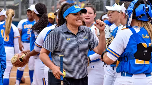 Softball coach talking with her players on the field between innings