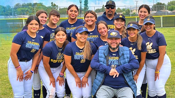 Youth softball team sitting on bench listening to coach's instructions