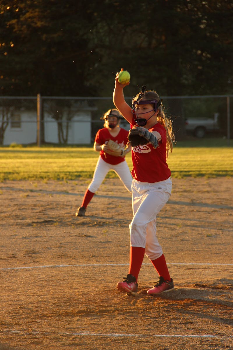 Youth softball pitcher warming up her arm with wrist snaps and short-toss progression before a game