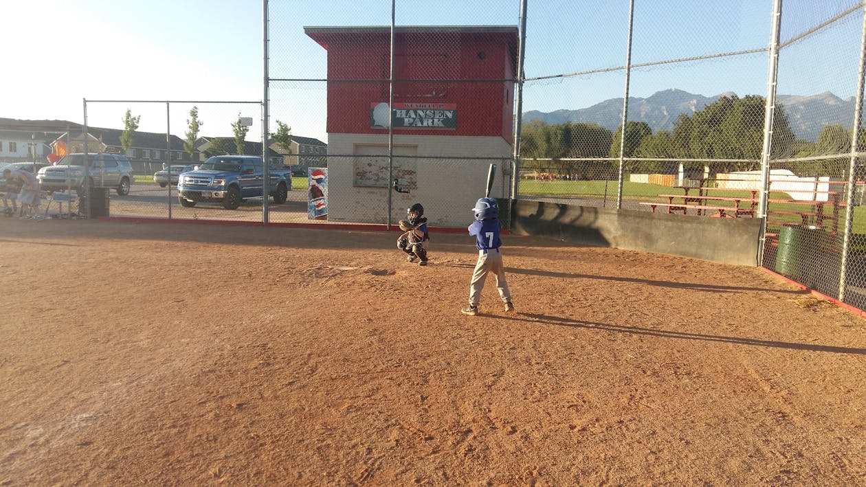 Youth baseball runner taking a lead off first base preparing to steal second during a game