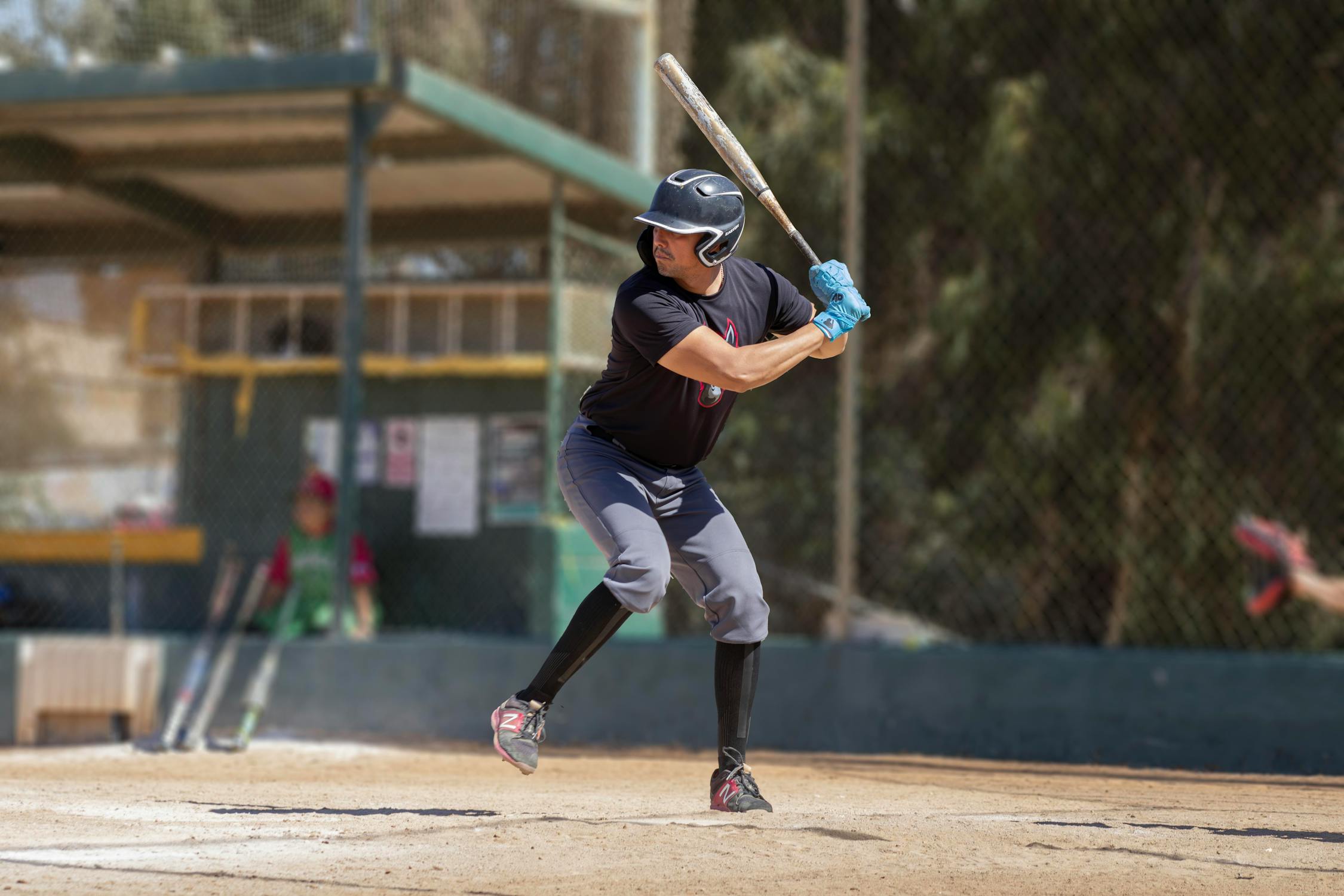 Youth baseball hitter reading a pitch with a disciplined plate approach during an at-bat