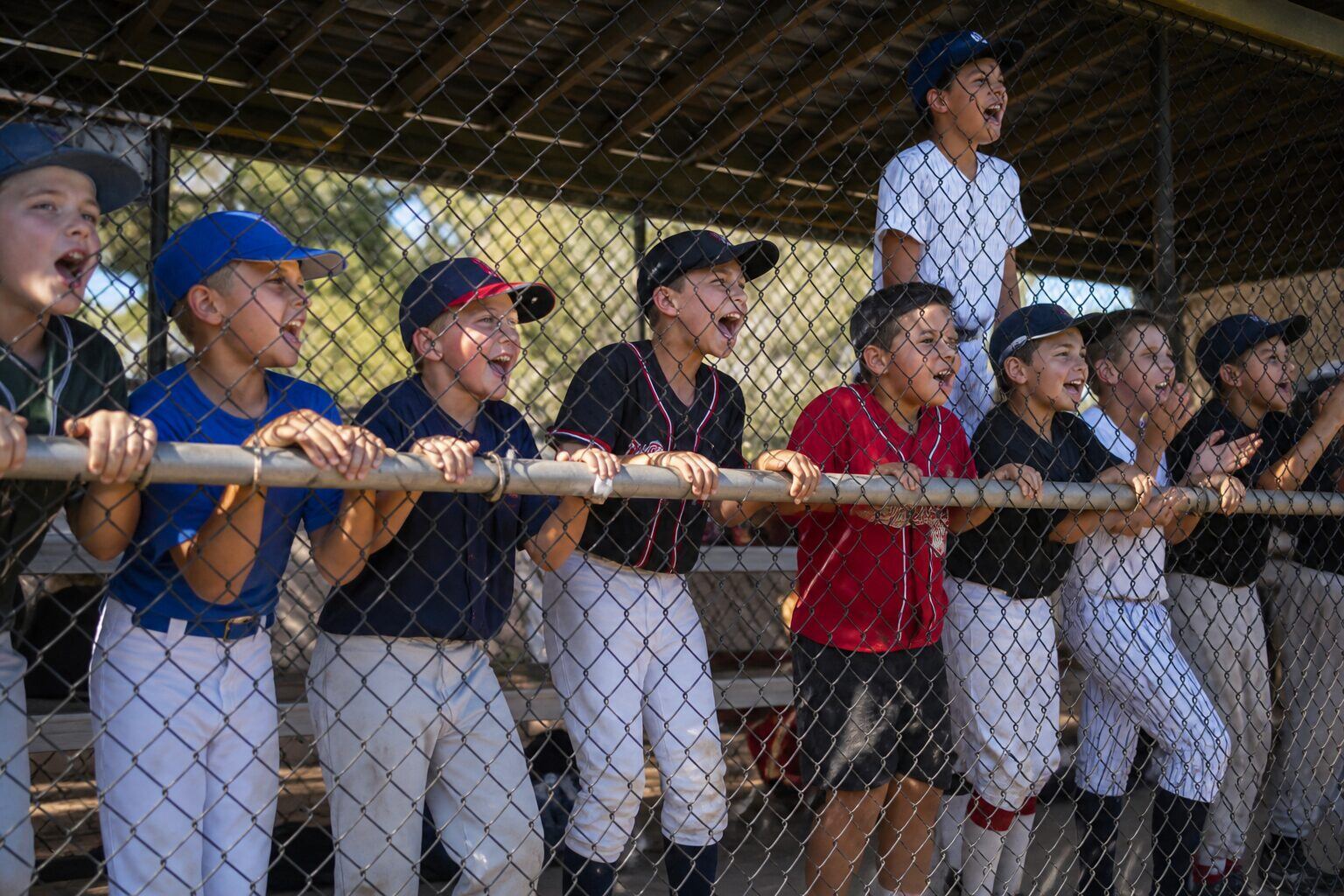 Youth baseball team cheering for a teammate from the dugout fence